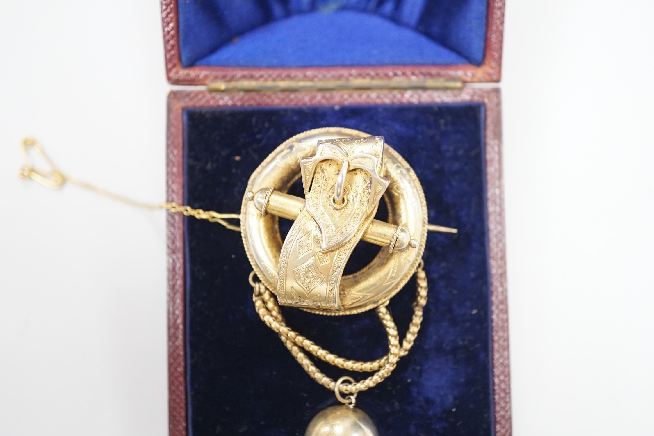A Victorian gilt white metal drop brooch, with central buckle motif and spherical drop, 80mm, in fitted leather case.